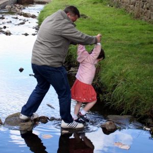 A man and a girl crossing a stream