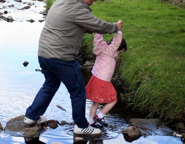 A man and a girl crossing a stream