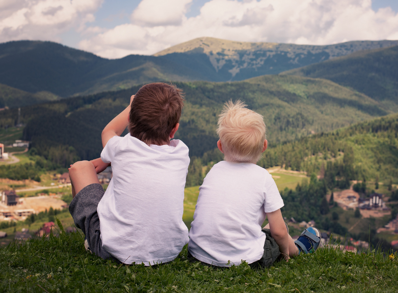 two brothers sitting on some grass