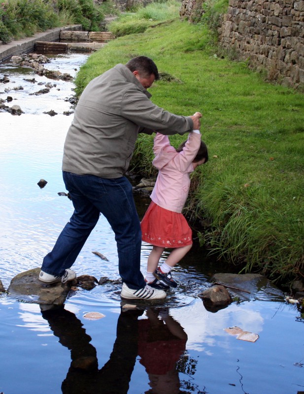 A man and a girl crossing a stream