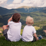 two brothers sitting on some grass