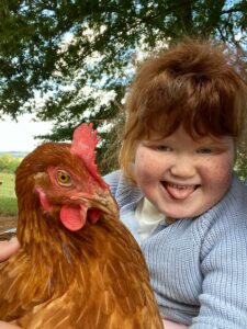 Bo poking her tongue out while holding a hen