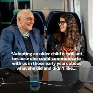 Carla sits on a train next her dad and her dad says he adopted Carla as an older child