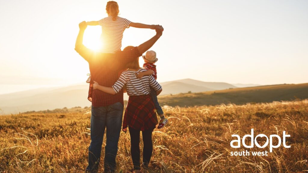 A family in late afternoon sunshine on the moors. The teenage child is sitting on their dad's shoulders.