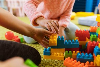 Children playing with colourful large building bricks.